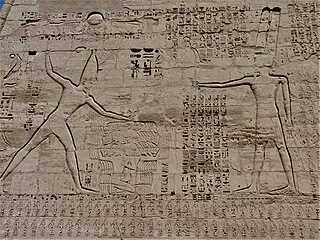 Ramses III holding the hair of his enemies, and the god Amun. Relief from Medinet Habu