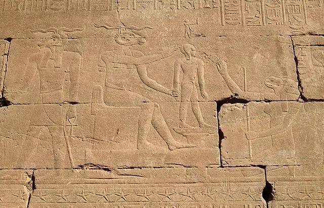 Khnum (left) fashions the god Ihy (middle) on a potter's wheel, with the help of the goddess Heqet, Dendera Temple.