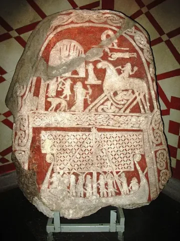 Berig, Tjängvide Picture Stone, Alskog Parish, Gotland, Sweden, 2008. CC BY-SA 4.0, via Wikimedia Commons**The Tjängvide Picture Stone**, from Gotland, Sweden. The upper scene is commonly interpreted as a fallen warrior arriving at Valhalla, where a woman, often identified as a Valkyrie, offers him a drinking horn. The rider appears on an eight-legged horse, which has encouraged comparisons with Odin’s horse Sleipnir. The interpretation is widely accepted but not certain.