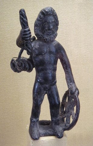 Bronze statuette of Taranis holding a wheel and thunderbolt, discovered at Le Châtelet de Gourzon, Haute-Marne, France. Gallo-Roman period. Collection of the Musée d'Archéologie nationale, Saint-Germain-en-Laye. Photograph by PHGCOM, via Wikimedia Commons. License: Public Domain (released by the photographer).